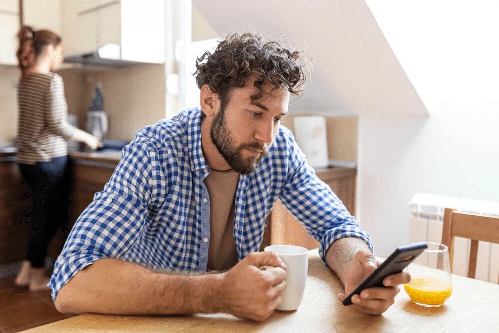 Eine Person hält ein Smartphone mit KI-Tools 2025, die den Alltag erleichtern, vor einem hellen Hintergrund.