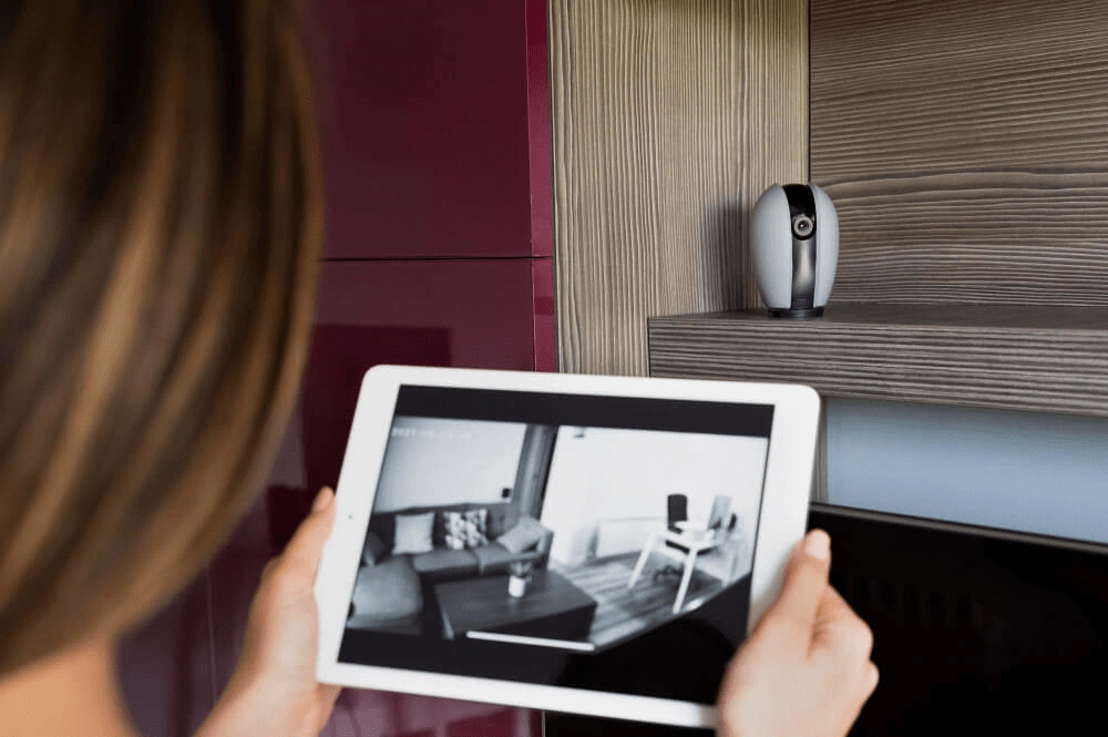 Tablet zeigt Live-Übertragung einer Überwachungskamera im Wohnzimmer – Teil eines Smart-Home-System

